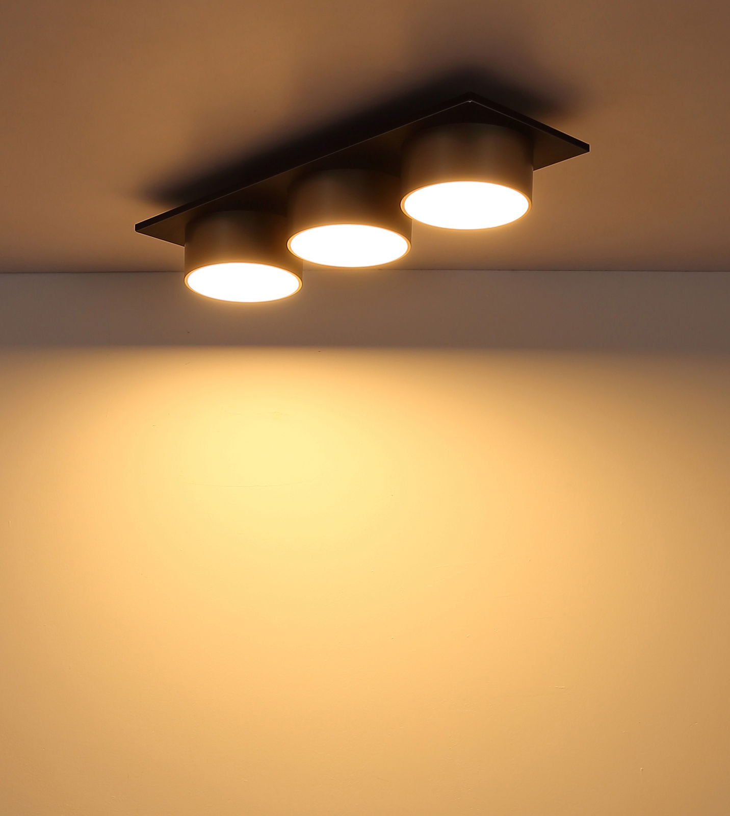 Moderne Deckenleuchte mit drei runden, leuchtenden Spots, von unten betrachtet.