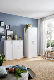 Weiße Schränke in einem modernen Wohnzimmer mit blauer Wand und großem Fenster, seitliche Perspektive.