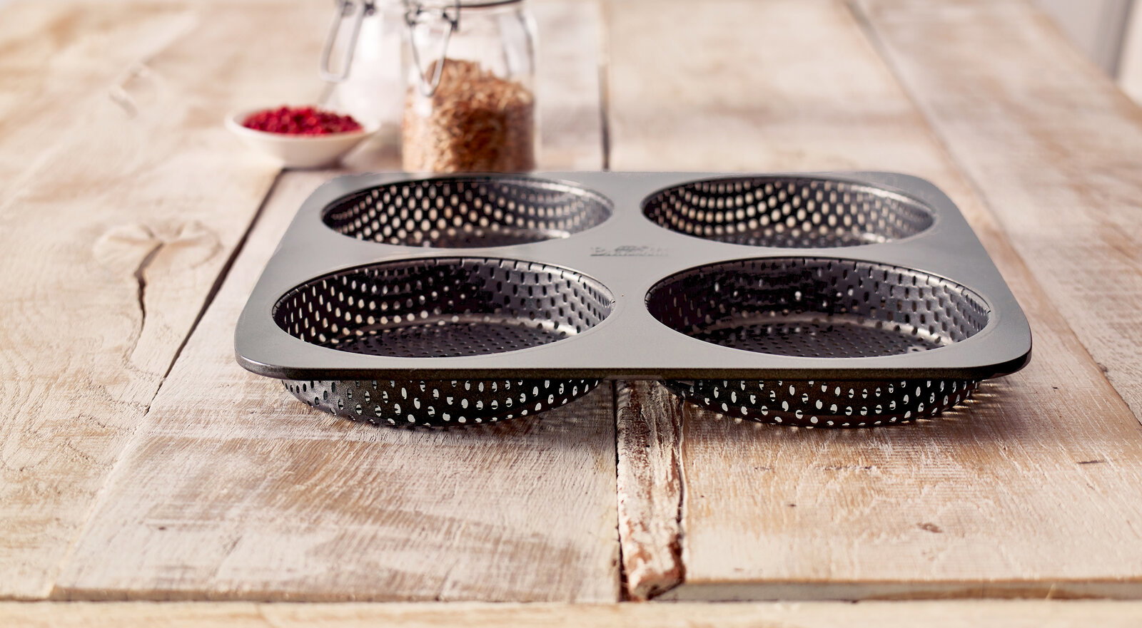 Burger Brötchen-Blech mit vier runden Formen, auf einem Holztisch von der Seite fotografiert.