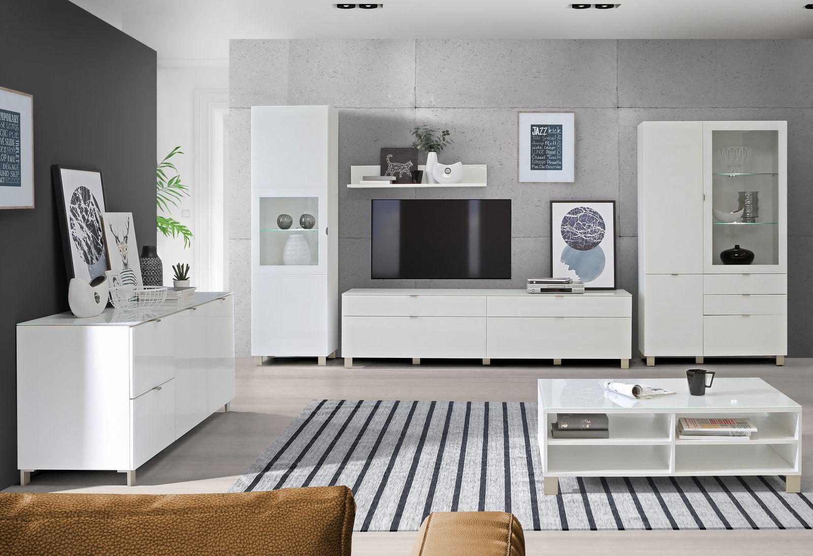 Moderne Wohnzimmermöbel in Weiß, bestehend aus einem TV-Lowboard, Hängeschränken, Vitrinen und einem Couchtisch, aus der Perspektive eines gemütlichen Wohnzimmers.