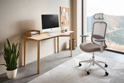 Moderner Drehstuhl mit ergonomischem Design, seitliche Perspektive, in einem hellen Büro neben einem Schreibtisch mit Computer.