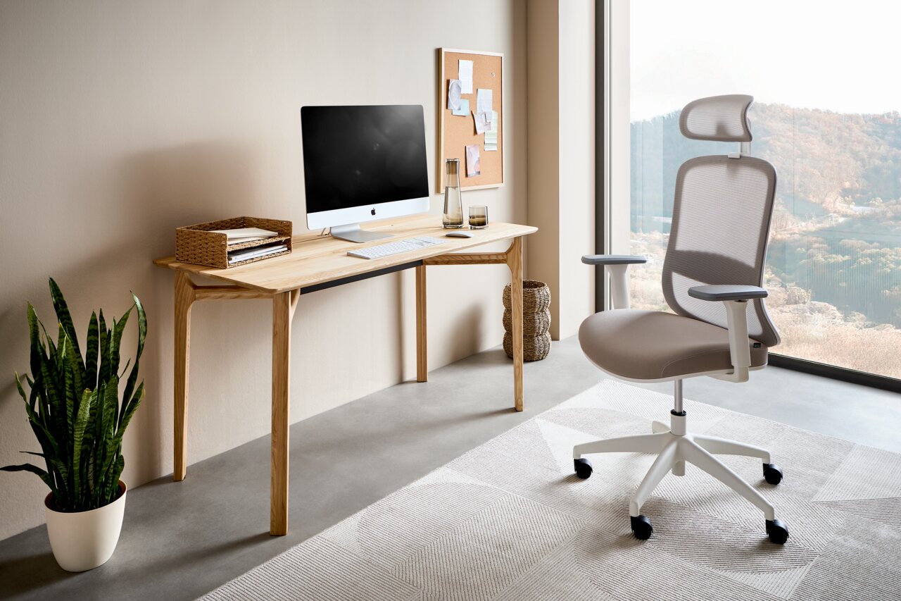 Moderner Drehstuhl mit ergonomischem Design, seitliche Perspektive, in einem hellen Büro neben einem Schreibtisch mit Computer.