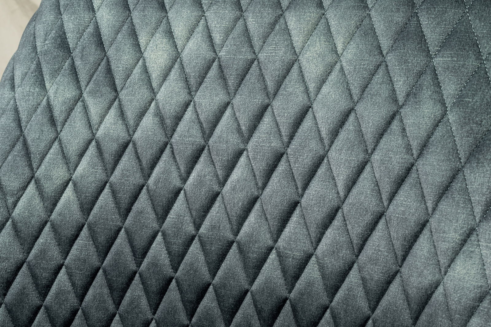 Nahaufnahme der gepolsterten Rückenlehne eines Drehstuhls mit grauem, rautenförmigem Steppmuster.