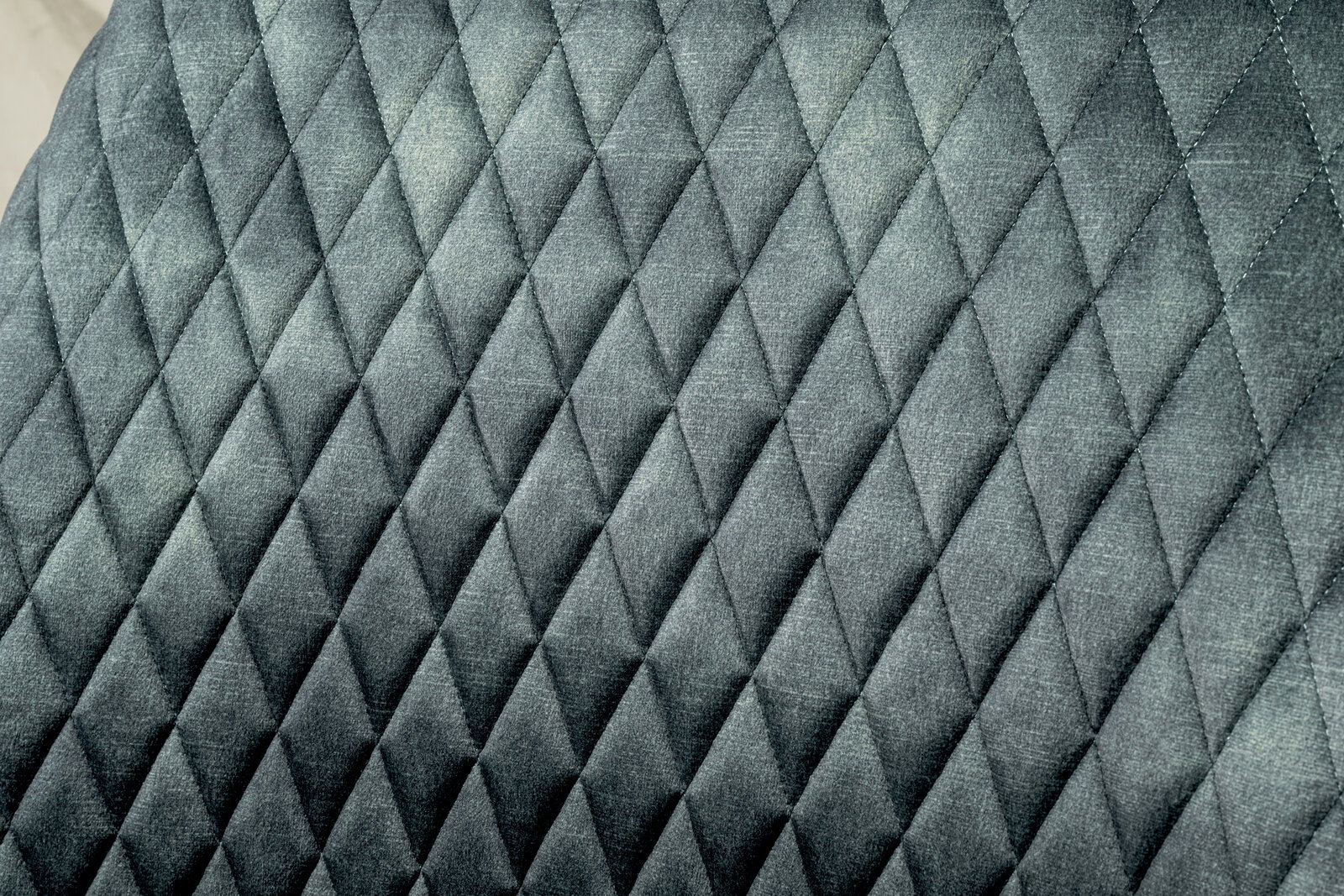 Nahaufnahme der gepolsterten Rückenlehne eines Drehstuhls mit grauem, rautenförmigem Steppmuster.