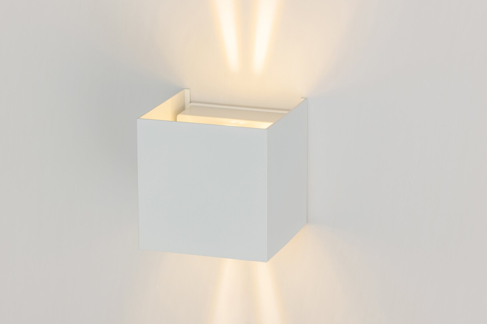Moderne LED-Wandleuchte in Weiß, die sowohl nach oben als auch nach unten Licht abstrahlt. Perspektive von der Seite.
