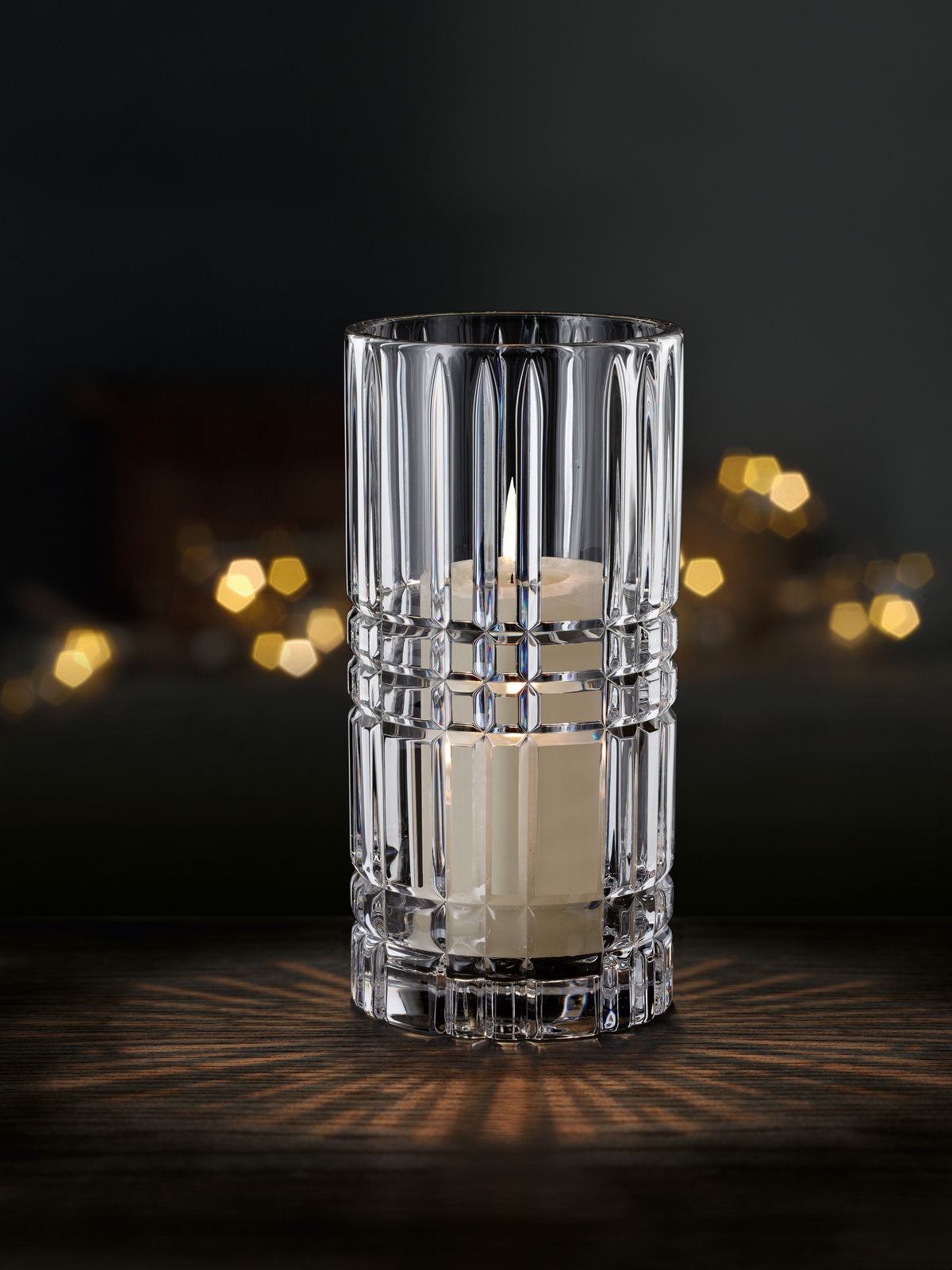 Kristallklare Vase oder Windlicht mit Kerze, frontal fotografiert, auf dunklem Hintergrund mit Lichteffekten.