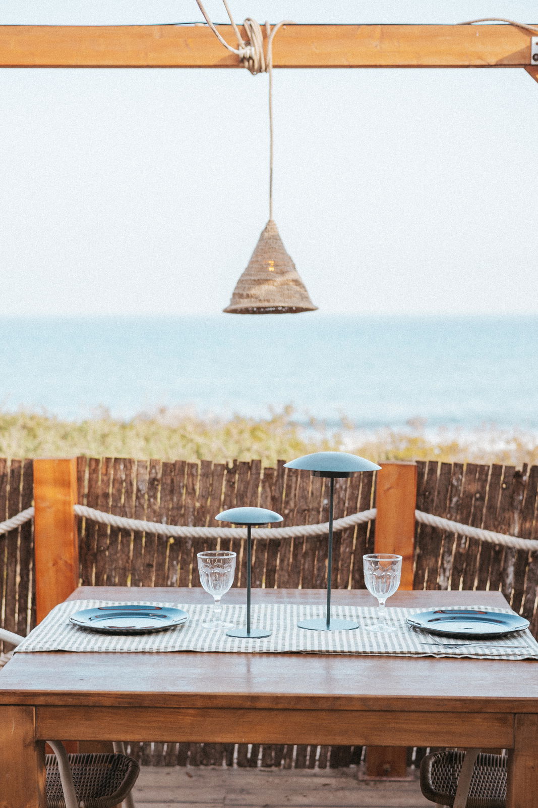 Outdoor-Hängeleuchte über einem Tisch mit Meeresblick, aus seitlicher Perspektive fotografiert.