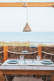 Outdoor-Hängeleuchte über einem Tisch mit Meeresblick, aus seitlicher Perspektive fotografiert.