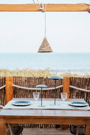 Outdoor-Hängeleuchte über einem Tisch mit Meeresblick, aus seitlicher Perspektive fotografiert.