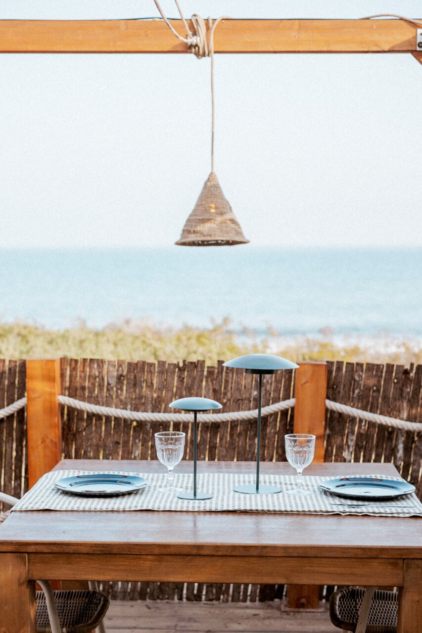 Outdoor-Hängeleuchte über einem Tisch mit Meeresblick, aus seitlicher Perspektive fotografiert.