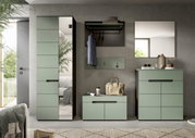 Frontalansicht eines modernen Flurmöbel-Sets in Salbeigrün mit hohem Garderobenschrank mit Spiegel, Wandgarderobe mit Hutablage und Haken, Sitzbank sowie Kommode unter einem Wandspiegel vor grauer Betonwand.