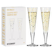 Zwei elegante Champagnergläser mit goldenen und schwarzen Sternmotiven, präsentiert in einer stilvollen Verpackung. Frontalansicht.