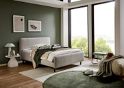 Modernes Polsterbett in einem stilvollen Schlafzimmer mit grüner Wand, großen Fenstern und minimalistischer Dekoration, seitliche Perspektive.