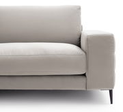 Nahaufnahme eines modernen, beigen Sofas mit Armlehne und schwarzem Bein, seitliche Perspektive