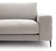 Nahaufnahme eines modernen, beigen Sofas mit Armlehne und schwarzem Bein, seitliche Perspektive