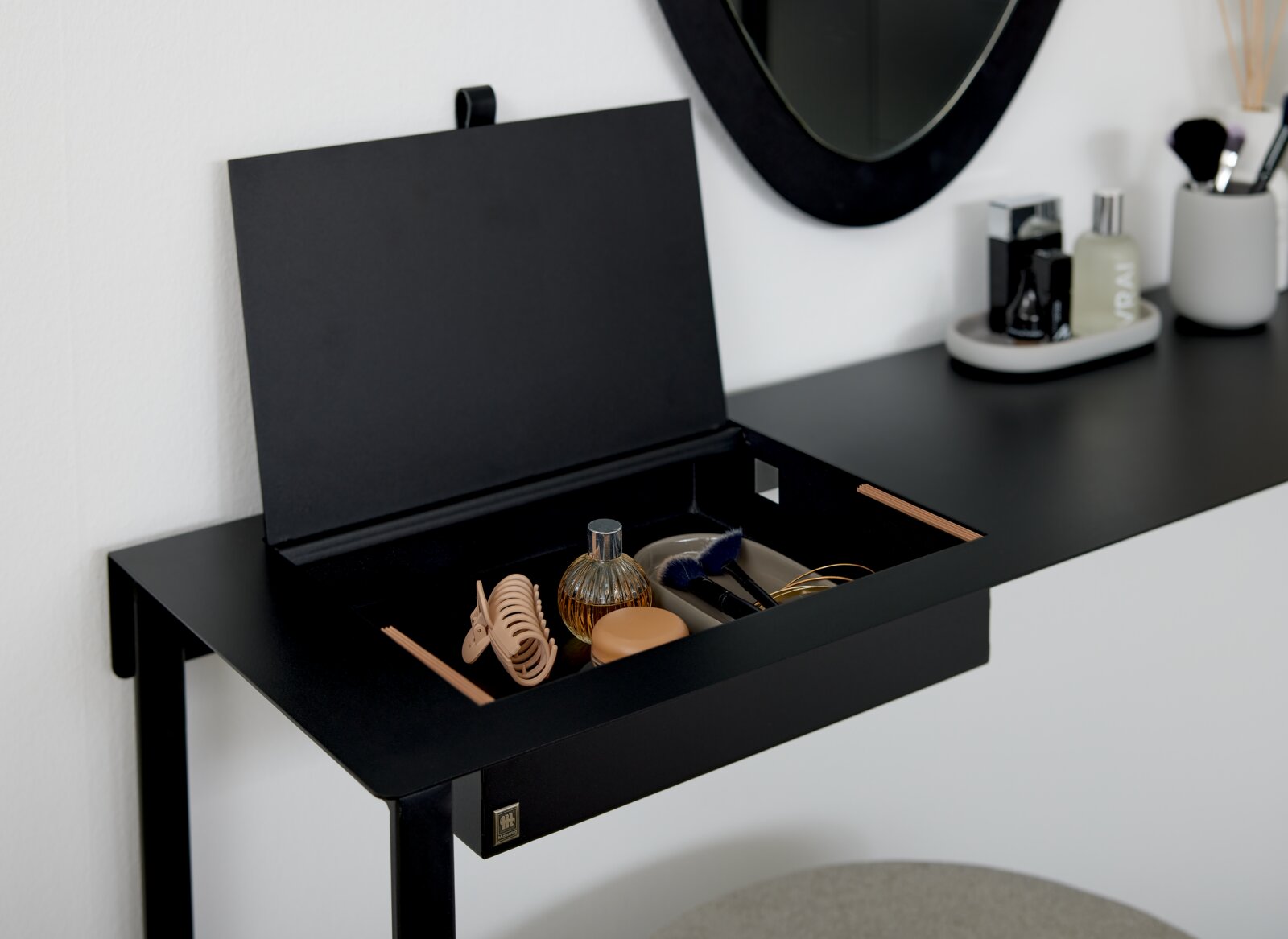 Zwarte consoletafel met een open vak waarin diverse accessoires zijn opgeborgen, gezien vanaf de zijkant.