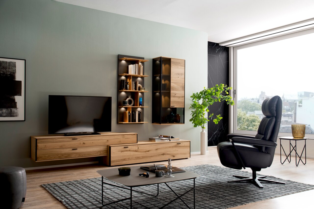 Moderner schwarzer Relaxsessel, drehbar, in einem stilvoll eingerichteten Wohnzimmer mit Blick von der Seite.