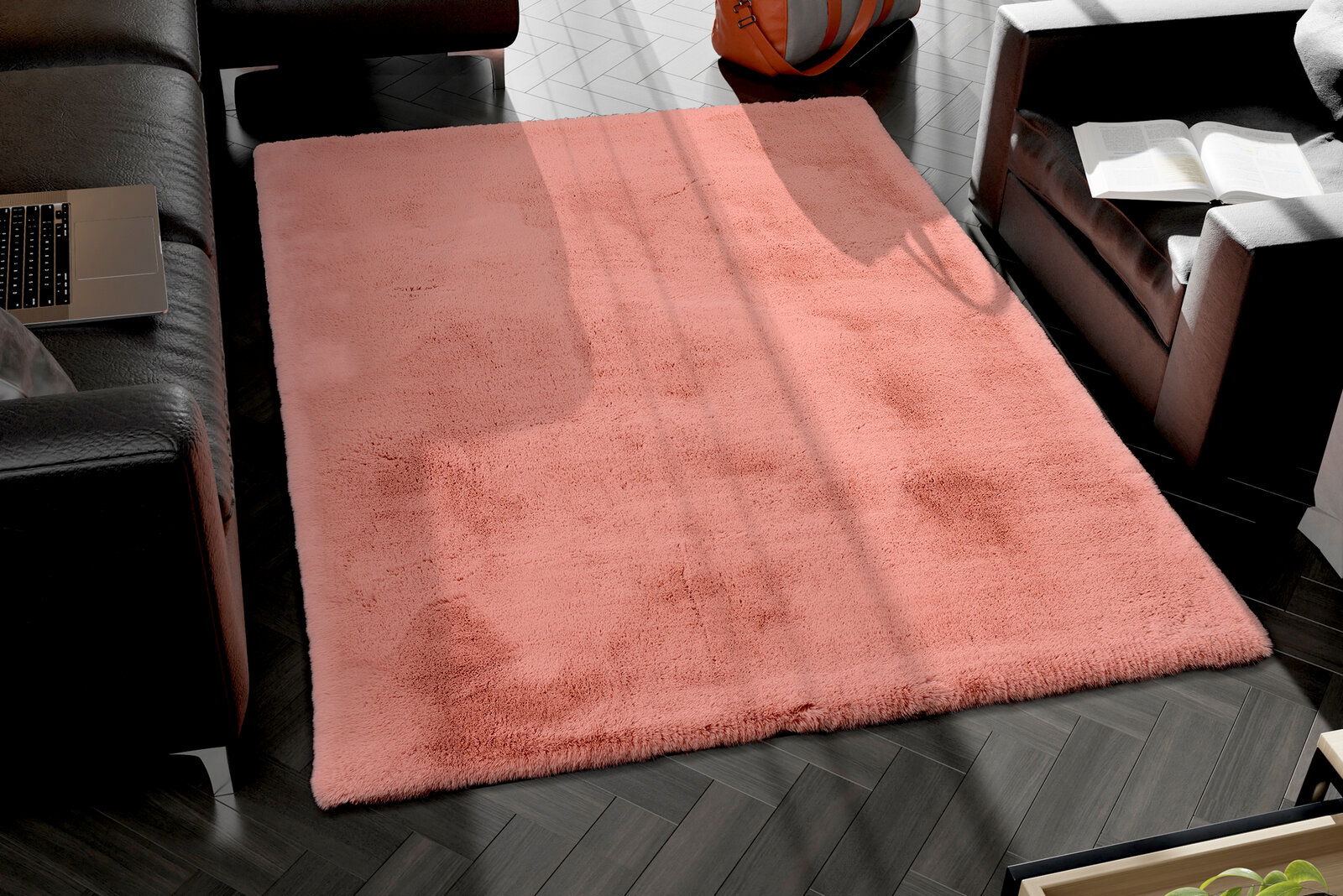 Rosa Fellteppich in einem modernen Wohnzimmer, von oben betrachtet, umgeben von schwarzen Ledersofas und einem Laptop.