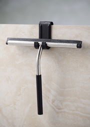 Badabstreifer mit Aufhängung, frontal an einer Duschwand befestigt, mit schwarzem Griff und Metallstange.