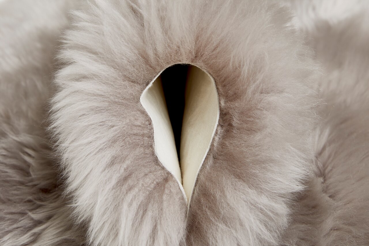 Nahaufnahme eines weichen, flauschigen Schaffells in grauer Farbe, das von oben betrachtet wird.