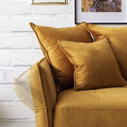 Nahaufnahme eines senfgelben Big-Sofas mit weichen Kissen, seitliche Perspektive.