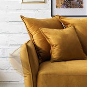 Nahaufnahme eines senfgelben Big-Sofas mit weichen Kissen, seitliche Perspektive.