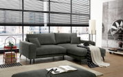 Modernes graues Ecksofa mit Recamiere in einem hellen Loft-Wohnzimmer vor großen Fenstern mit Jalousien, frontal in leichter Schrägansicht aufgenommen
