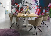 Esszimmer mit einem Holztisch und vier drehbaren Armlehnstühlen der Serie FRISCO von Set One by Musterring, vor einer bunten Wand mit Kunstmotiv. Perspektive: seitlich.