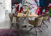 Esszimmer mit einem Holztisch und vier drehbaren Armlehnstühlen der Serie FRISCO von Set One by Musterring, vor einer bunten Wand mit Kunstmotiv. Perspektive: seitlich.