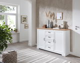 Weißes Sideboard mit Holzplatte, dekoriert mit Vasen und Kunstobjekten, in einem modernen Wohnzimmer mit Blick auf die rechte Seite.