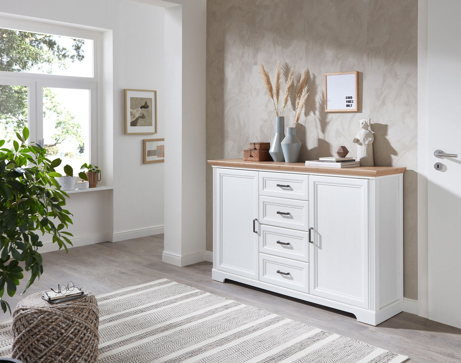 Weißes Sideboard mit Holzplatte, dekoriert mit Vasen und Kunstobjekten, in einem modernen Wohnzimmer mit Blick auf die rechte Seite.