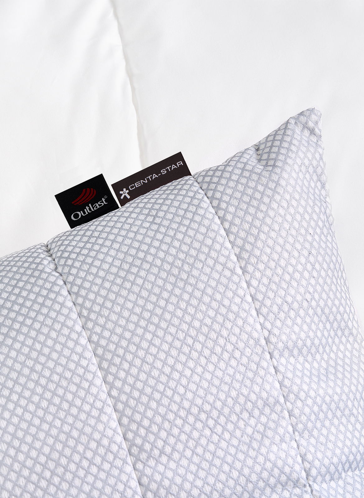 Gestepptes Kissen 80x80cm mit geometrischem Muster, Markenetiketten sichtbar, aus der Vogelperspektive fotografiert.