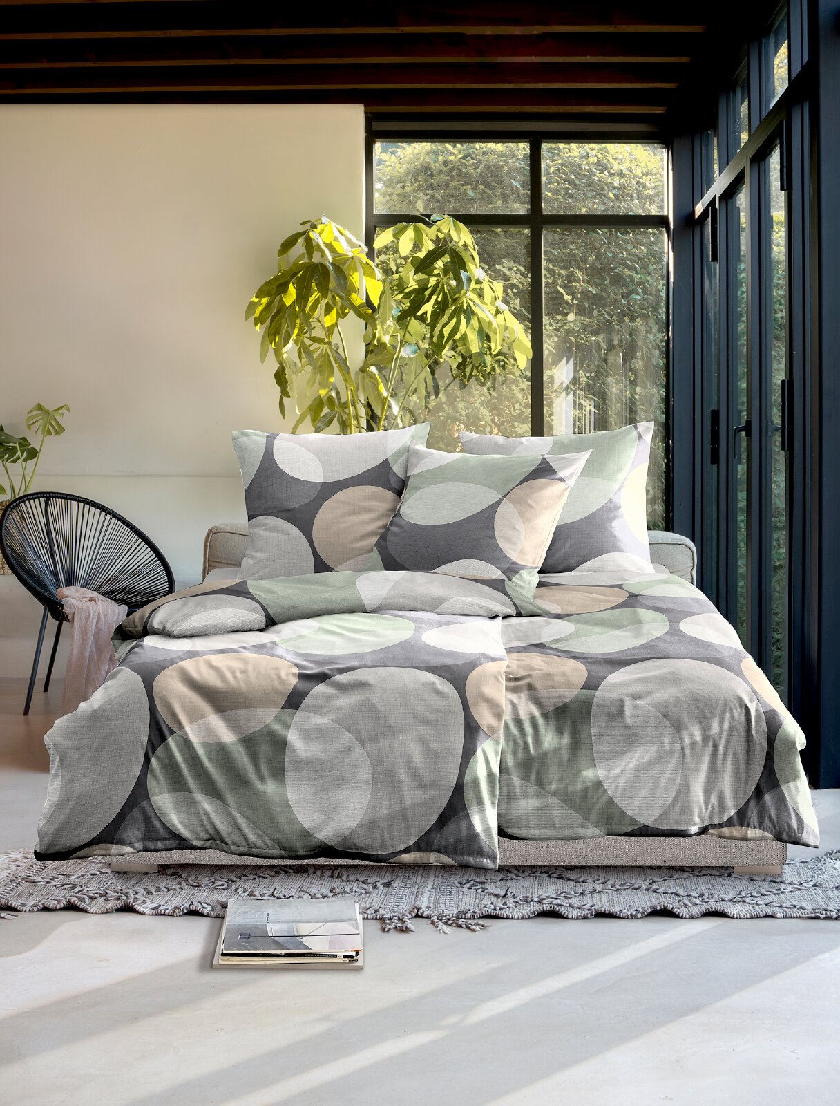 Vooraanzicht van modern beddengoed met groot cirkelpatroon in grijs, mintgroen, beige en wit, sfeervol gepresenteerd op een tweepersoonsbed in een lichte slaapkamer.