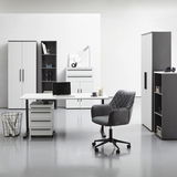 Moderne Büromöbel in einem hellen Raum, bestehend aus einem Winkelschreibtisch mit Rollcontainer, einem Drehstuhl und mehreren Aktenschränken und Regalen, frontal betrachtet.