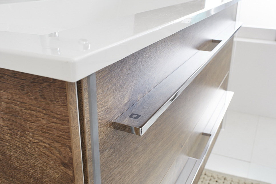 Nahaufnahme einer modernen Badkombination mit Holzoptik und glänzenden Metallgriffen, seitliche Perspektive.