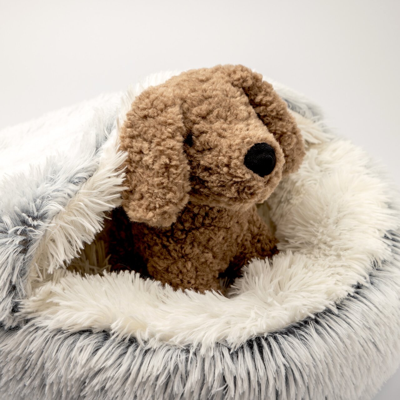 rogon Haustierbett SAMSON Plüschhund sitzt in einem flauschigen, runden Haustierbett mit weißem und grauem Kunstfell, seitliche Perspektive