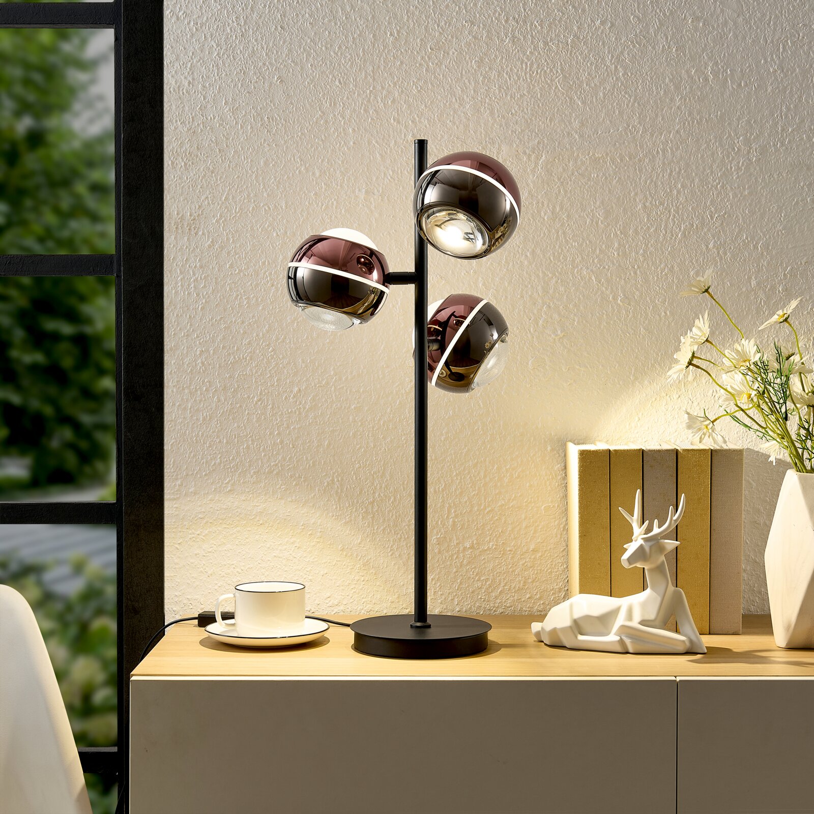 Dieter Knoll LED-Tischleuchte Moderne Tischlampe mit drei kugelförmigen, glänzenden Lampenköpfen in Kupfer/Chrom-Optik auf schwarzem Standfuß, frontal aus leichter Seitenperspektive auf einem Sideboard inszeniert.