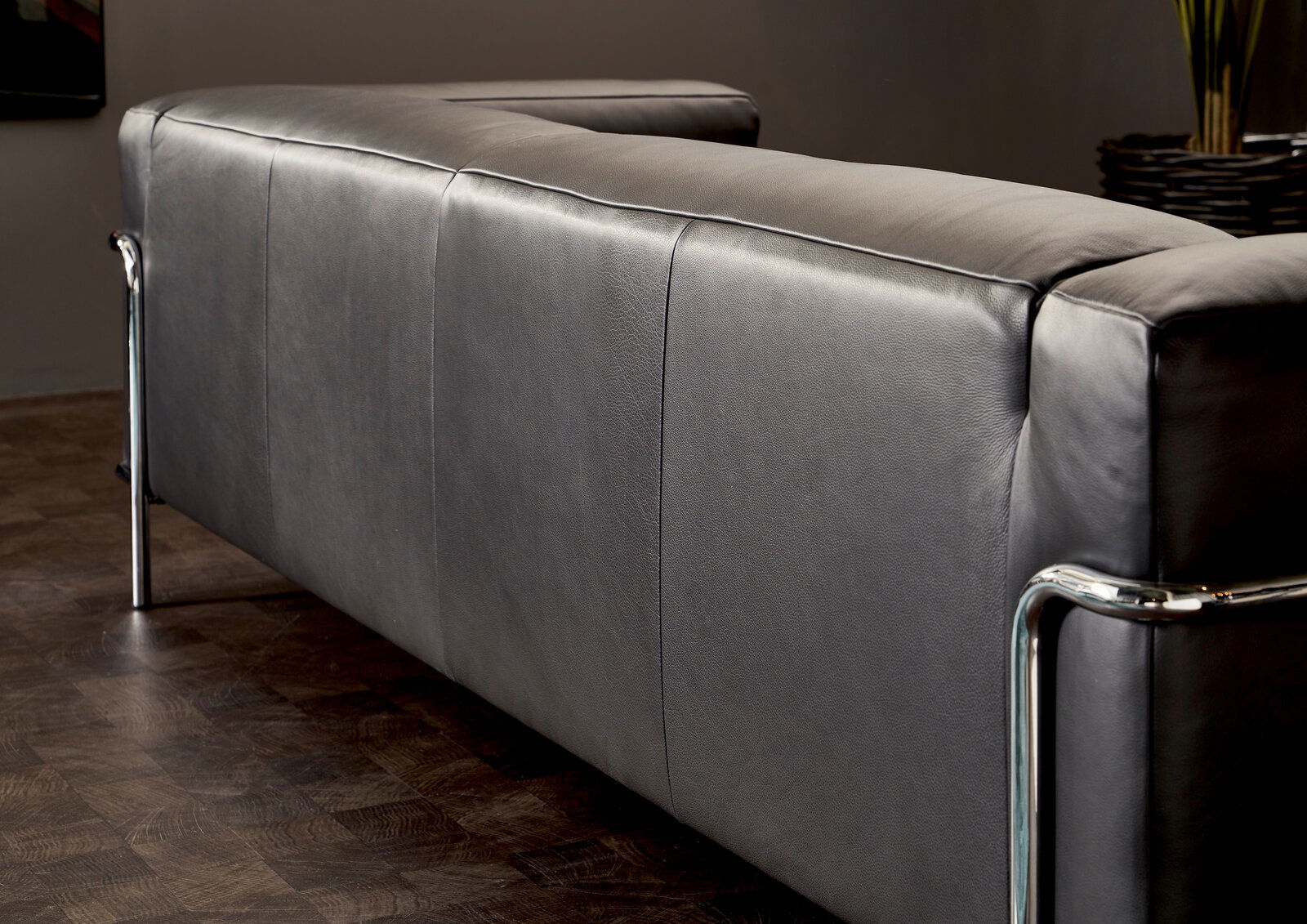 Rückansicht eines modernen grauen 3-Sitzer Sofas mit Metallrahmen in einem stilvollen Raum.