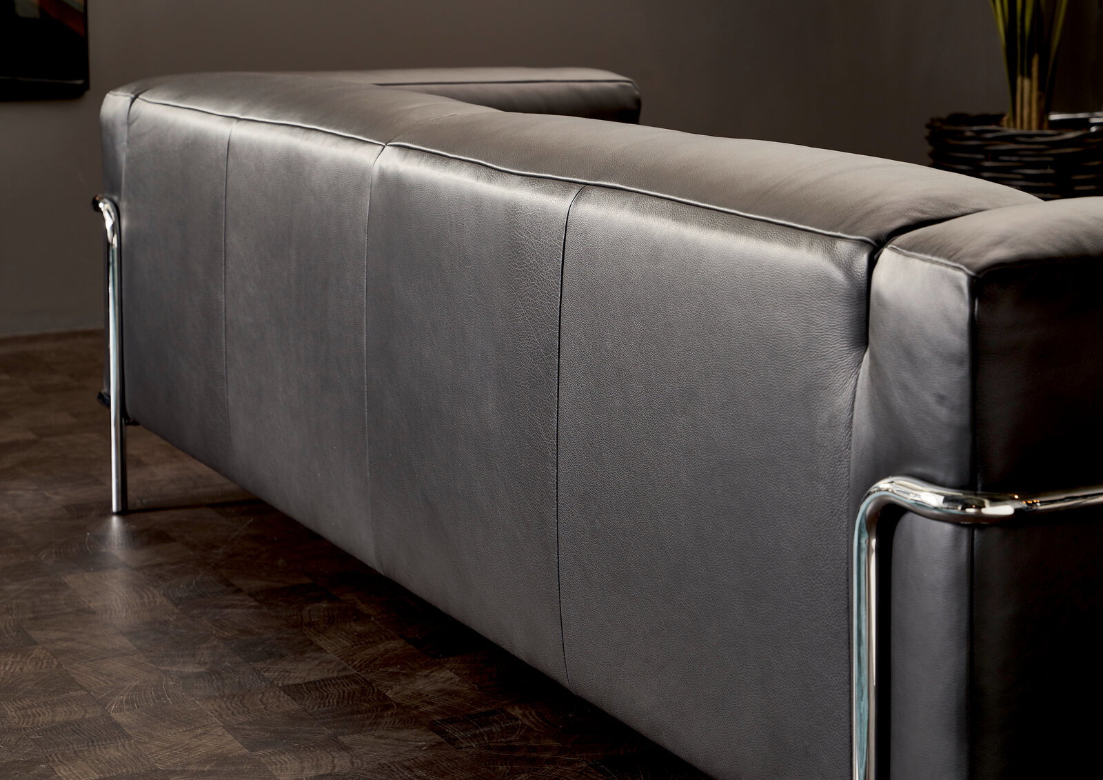 Rückansicht eines modernen grauen 3-Sitzer Sofas mit Metallrahmen in einem stilvollen Raum.