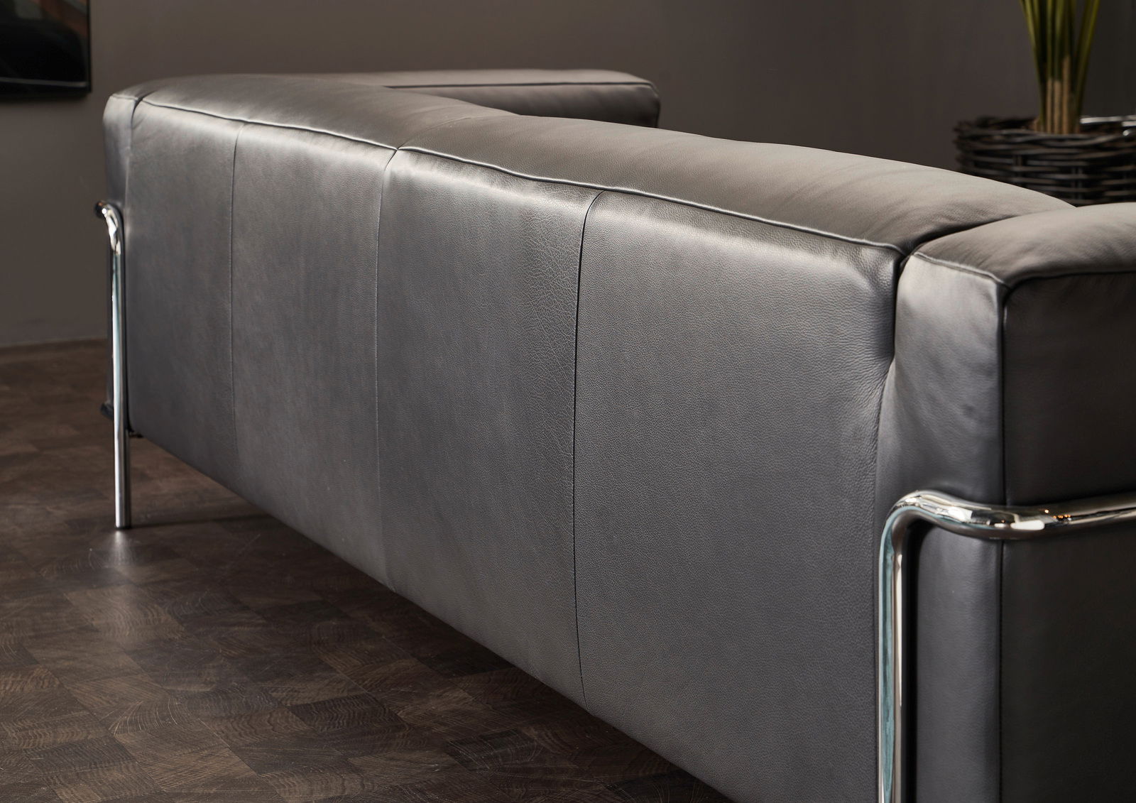 Rückansicht eines modernen grauen 3-Sitzer Sofas mit Metallrahmen in einem stilvollen Raum.
