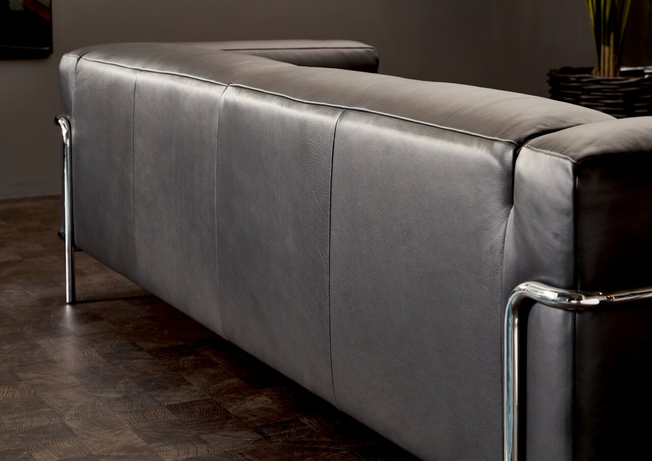 Rückansicht eines modernen grauen 3-Sitzer Sofas mit Metallrahmen in einem stilvollen Raum.