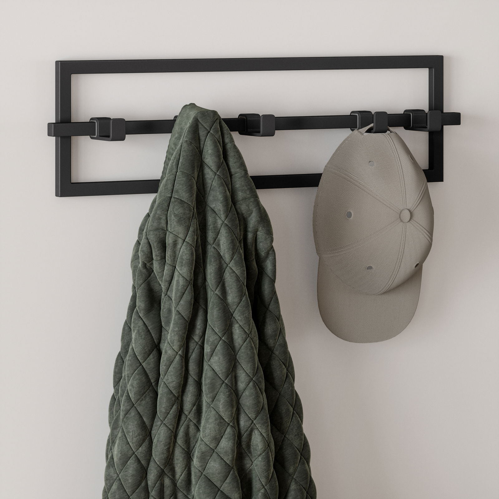Moderne Wandgarderobe CUBIKO von Umbra in schwarzem Metall mit mehreren Haken, frontal betrachtet, mit einer Jacke und einer Mütze behängt.