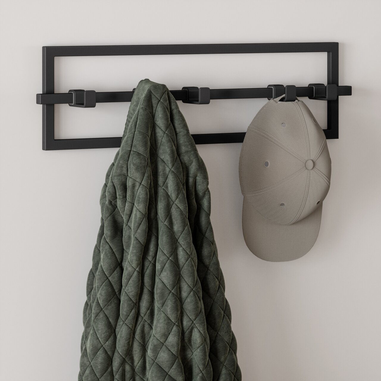 Moderne Wandgarderobe CUBIKO von Umbra in schwarzem Metall mit mehreren Haken, frontal betrachtet, mit einer Jacke und einer Mütze behängt.