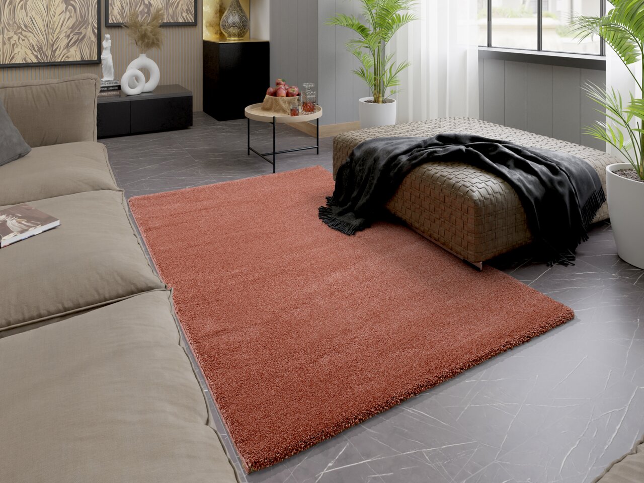 Ein moderner Wohnraum mit einem roten Uni-Teppich, der auf einem grauen Marmorboden liegt. Der Teppich ist von einem beigen Sofa und einem geflochtenen Hocker umgeben. Die Perspektive zeigt den Raum aus einer leicht erhöhten Position.