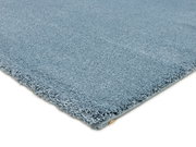 Nahaufnahme eines blauen Uni-Teppichs aus seitlicher Perspektive, der die weiche Textur und die Kanten zeigt.