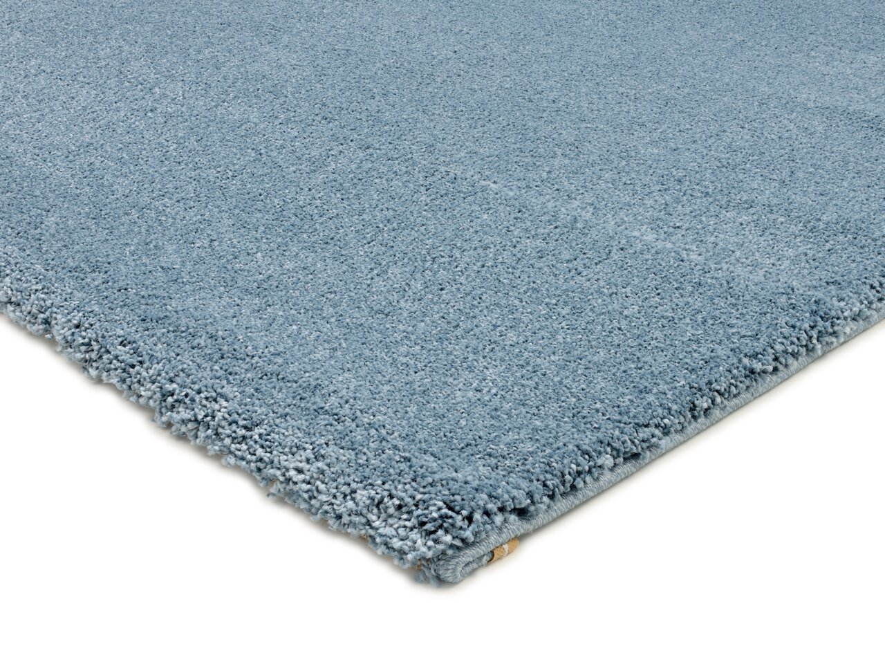 Nahaufnahme eines blauen Uni-Teppichs aus seitlicher Perspektive, der die weiche Textur und die Kanten zeigt.