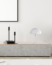 Moderne Tischleuchte MEIKE in Weiß auf einem grauen Sideboard, seitliche Perspektive