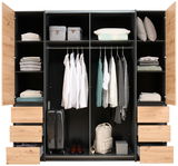 Offener Dreh- und Schwebetürenschrank mit vier Türen, gefüllt mit Kleidung, Koffern und Accessoires, aus der Frontansicht.