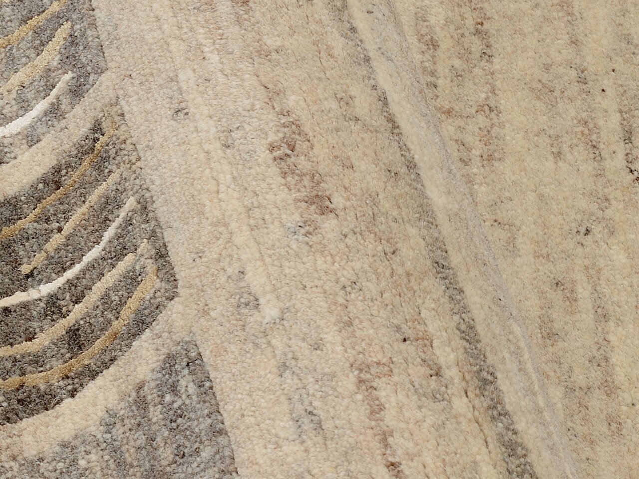 Nahaufnahme eines Wollteppichs mit beige und grauen Mustern, diagonale Perspektive
