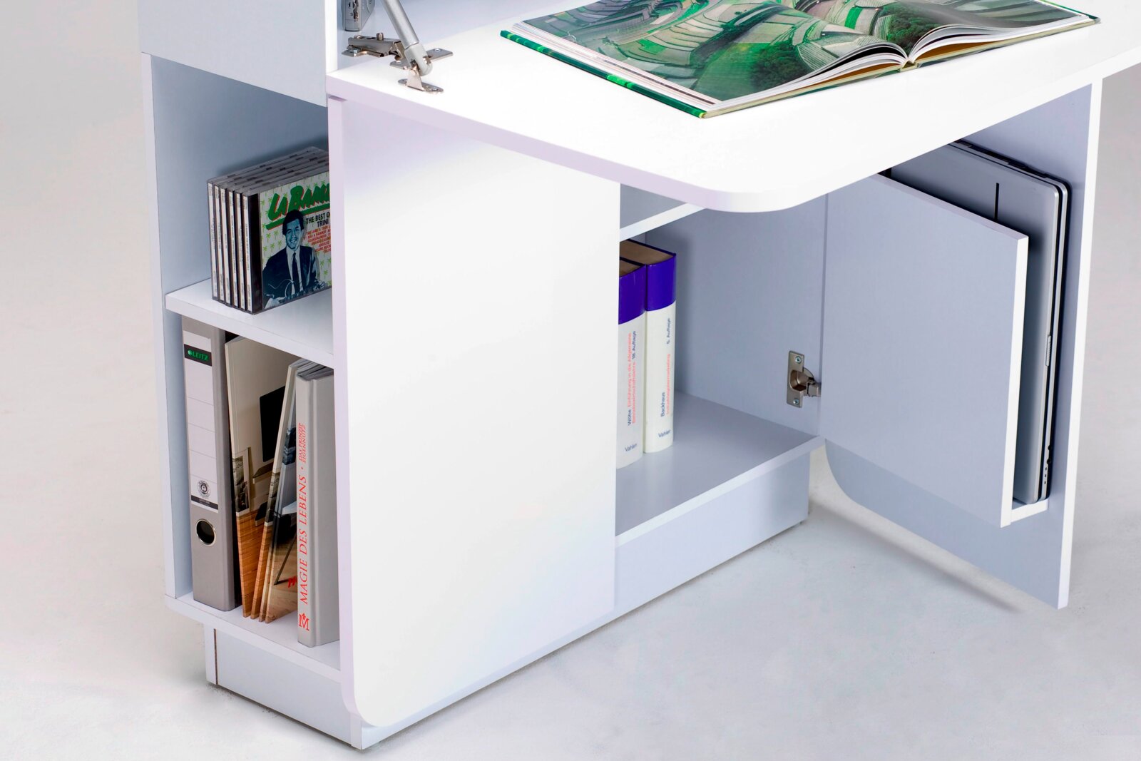 Witte secretaire met open planken, gevuld met boeken, ordners en cd’s, en een open kastdeur waarin een laptop te zien is. Aanzicht vanaf de zijkant.
